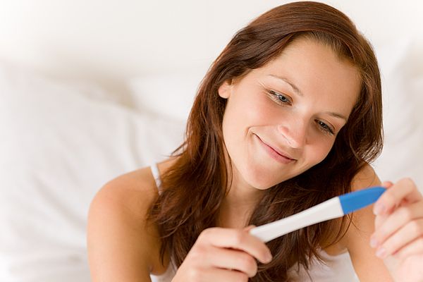 Glückliche Frau schaut auf ihren Schwangerschaftstest