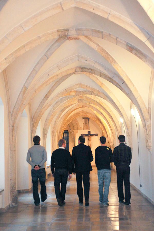 5 Priesterseminar Teilnehmer gehen einen Gang entlang