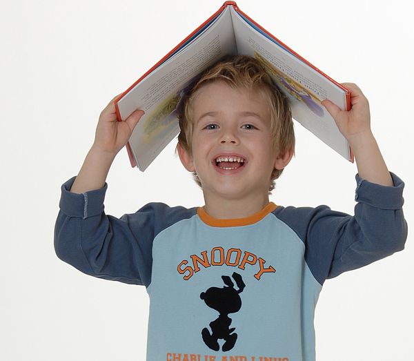 Kind hält sich dachförmig geöffnetes Buch über den Kopf