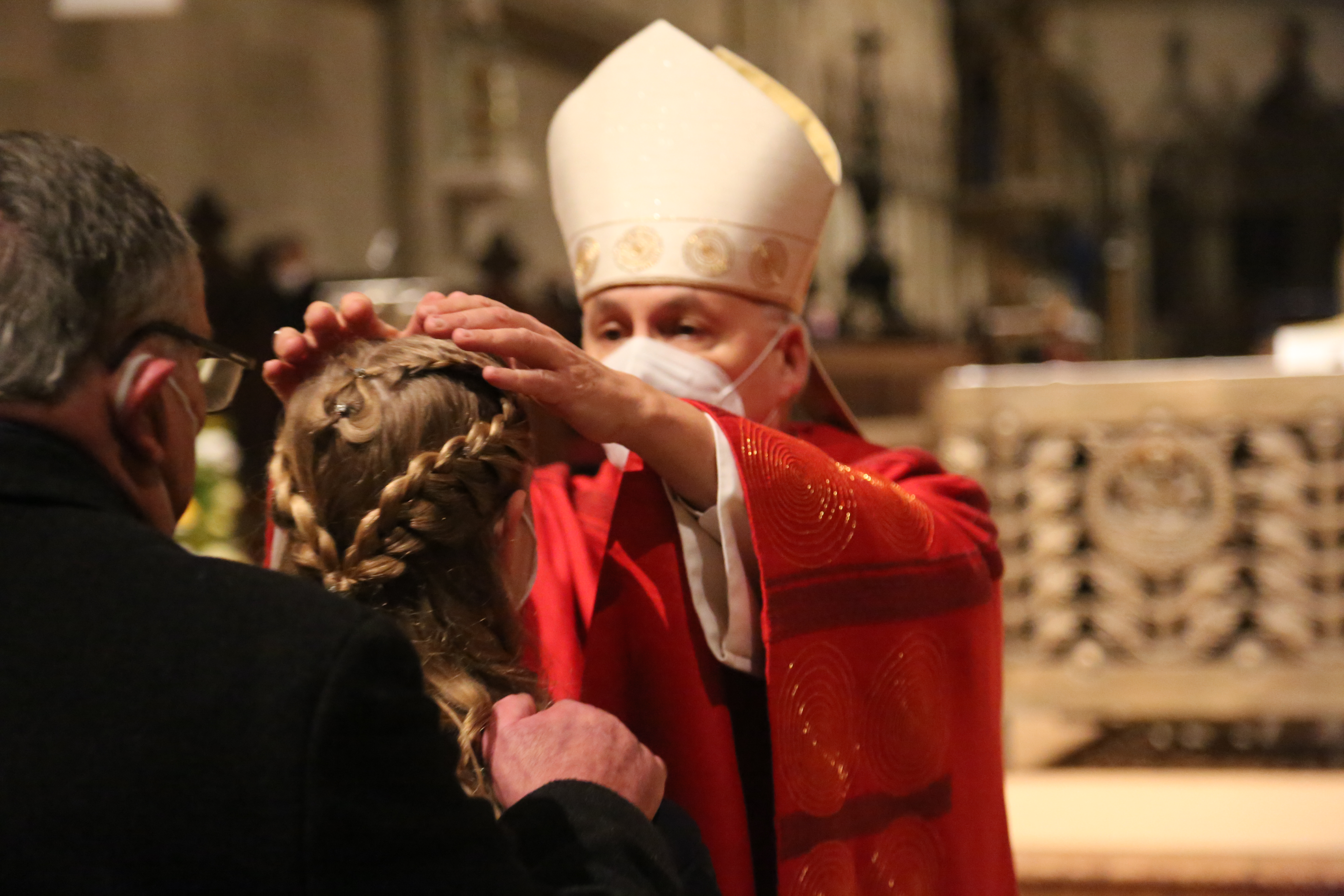 Bischof Rudolf legt einer Schülerin die Hand auf.