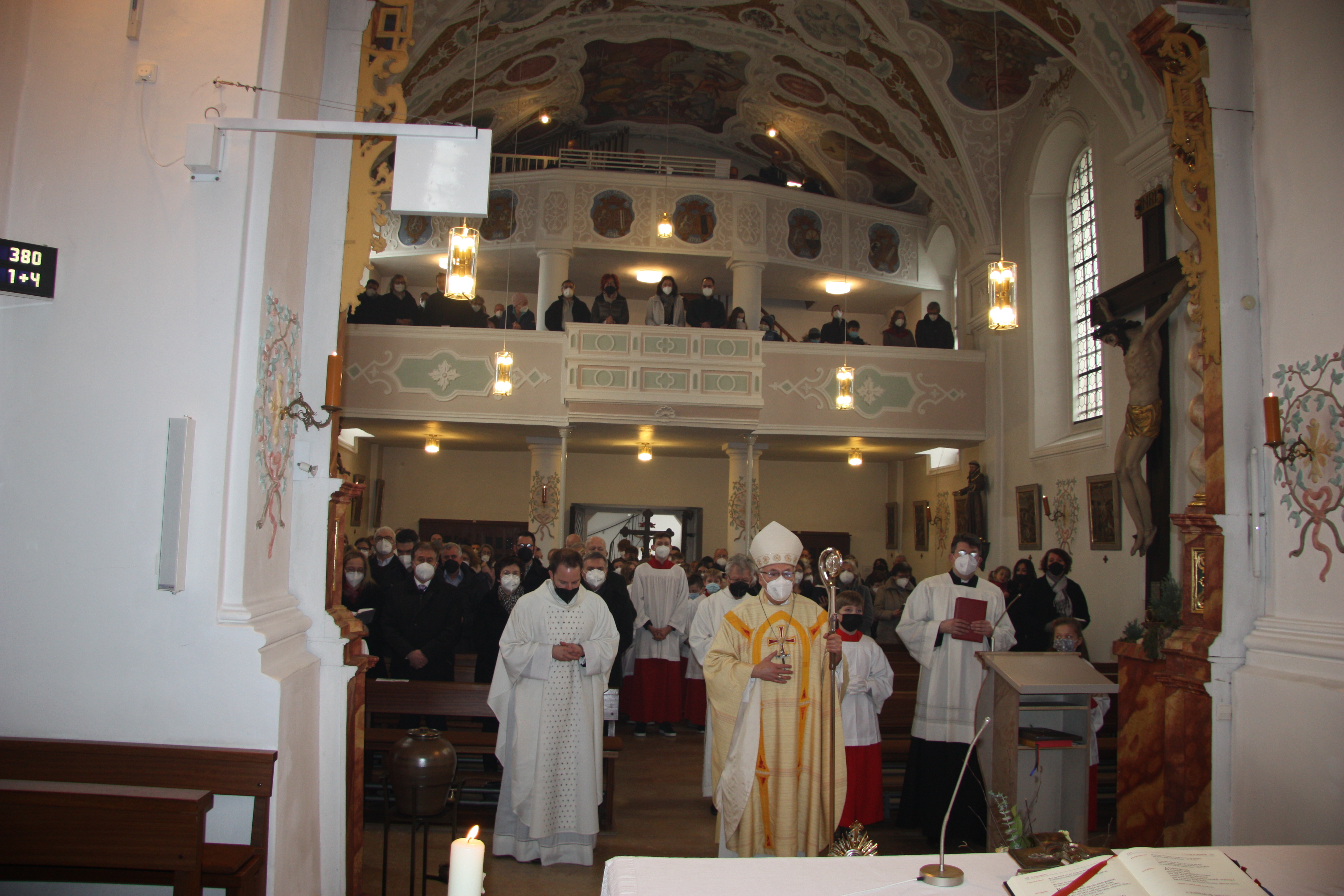 Bischof und Priester stehen in der Kirche vor dem Altar.