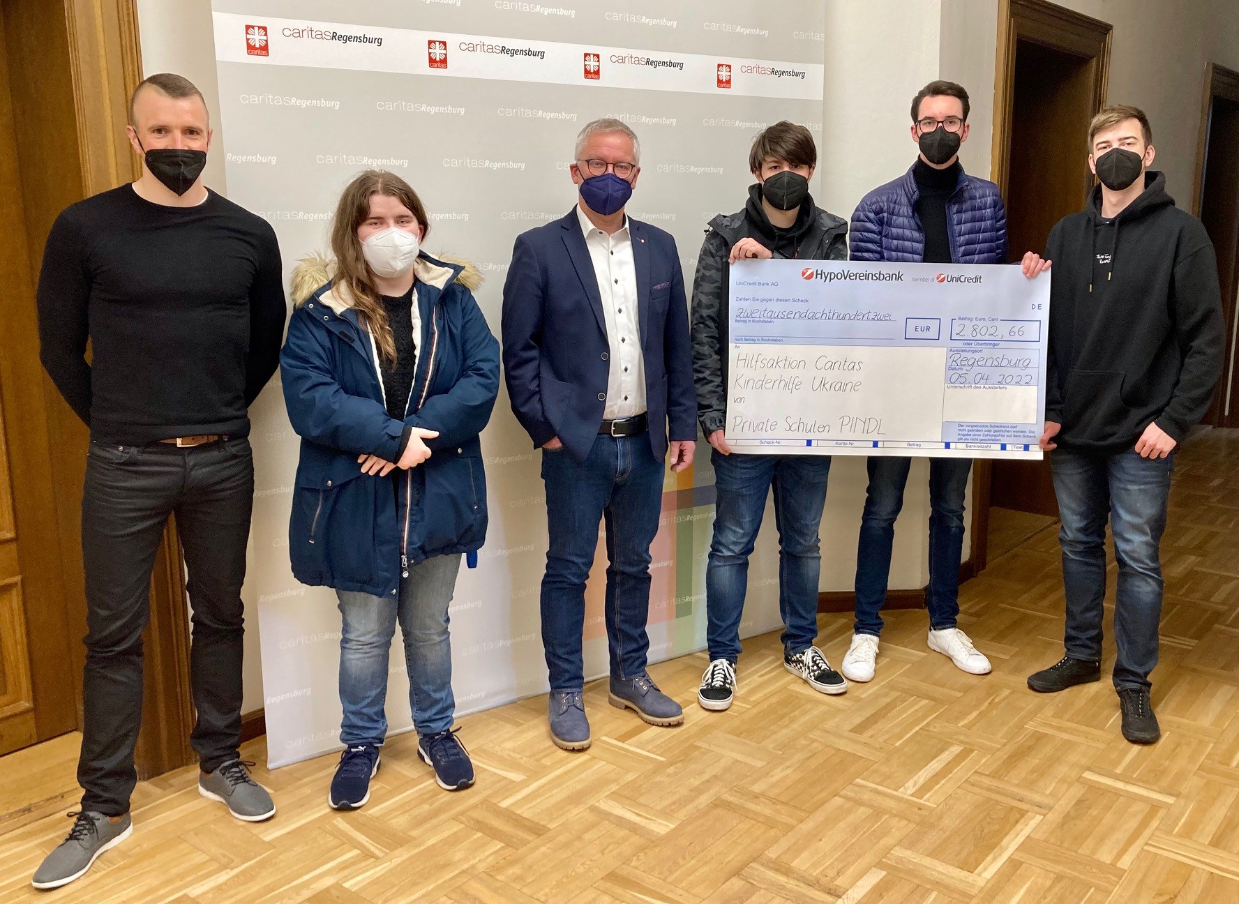 Internatsleiter Thomas Walther (li.) hat mit vier Pindl-Schülern symbolisch einen Scheck in Höhe von 2.800 Euro an Diözesan-Caritasdirektor Michael Weißmann übergeben.