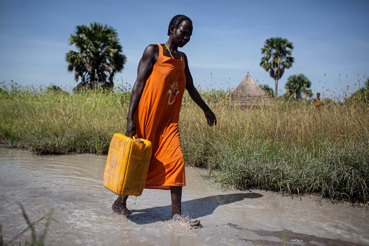 Sudanesische Frau trägt schweren Kanister mit Wasser