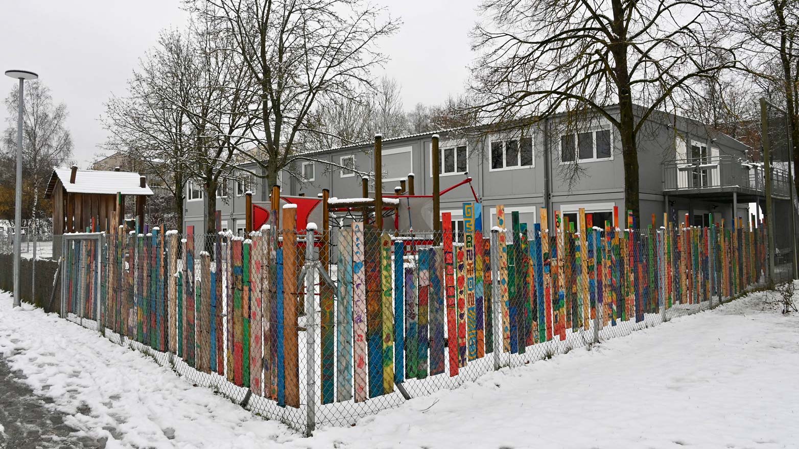 Kindergarten St. Josef im Winter hinter buntem Lattenzaun