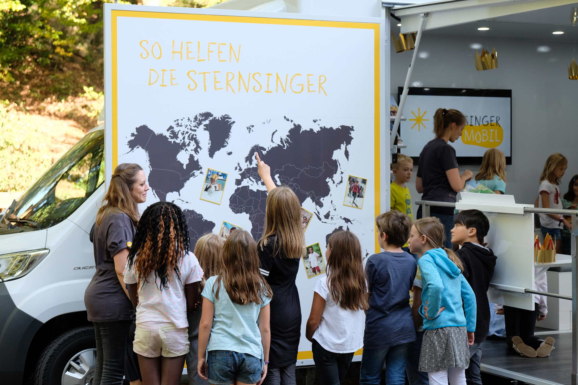 Kinder betrachten Weltkarte an aufgeklapppter Fahrzeugtür