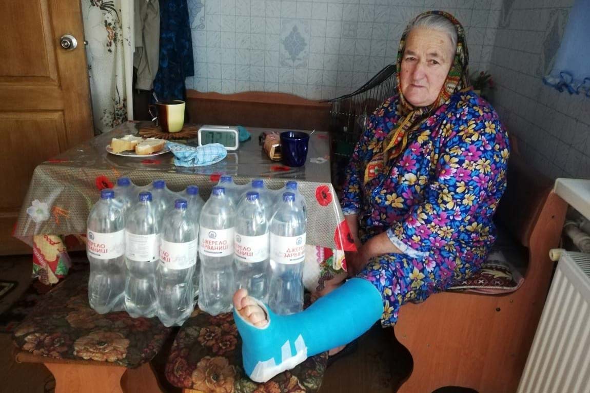 Eine ältere Frau erhält Trinkwasser in ihrem Zuhause. 