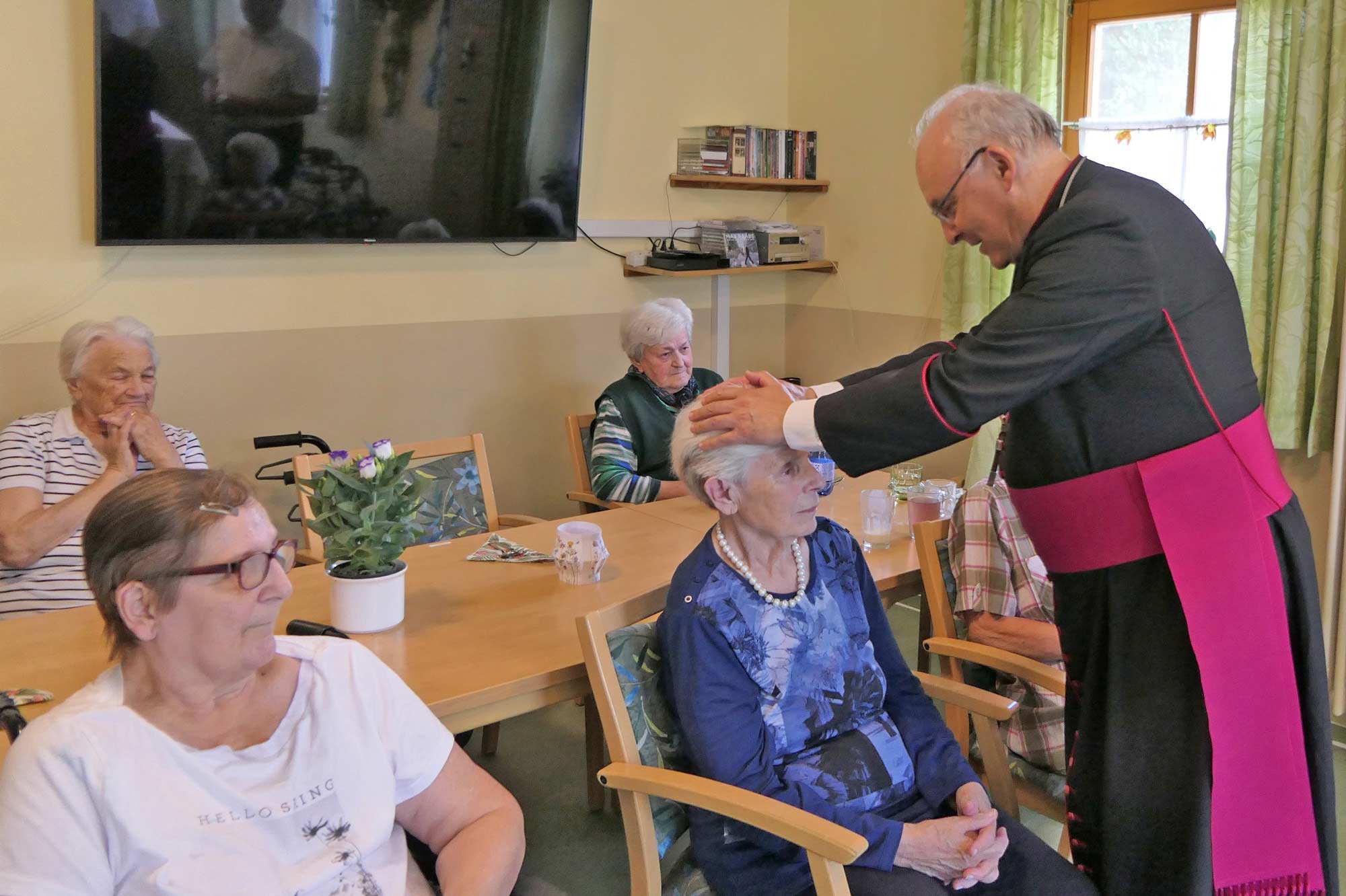 Bischof legt einer Seniorin die Hände zur Segnung auf