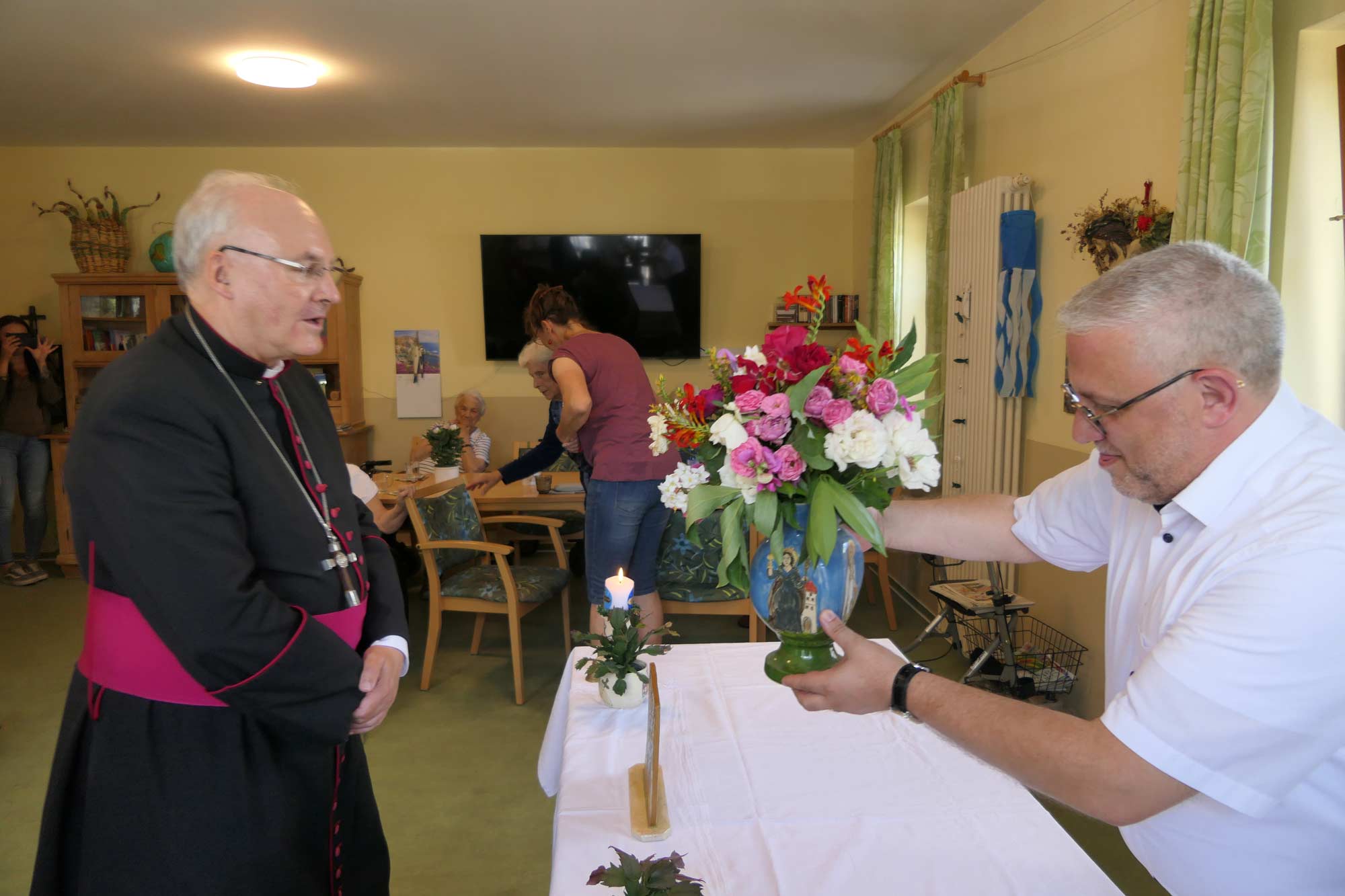 Ein Mann zeigt dem Bischof eine Blumenvase