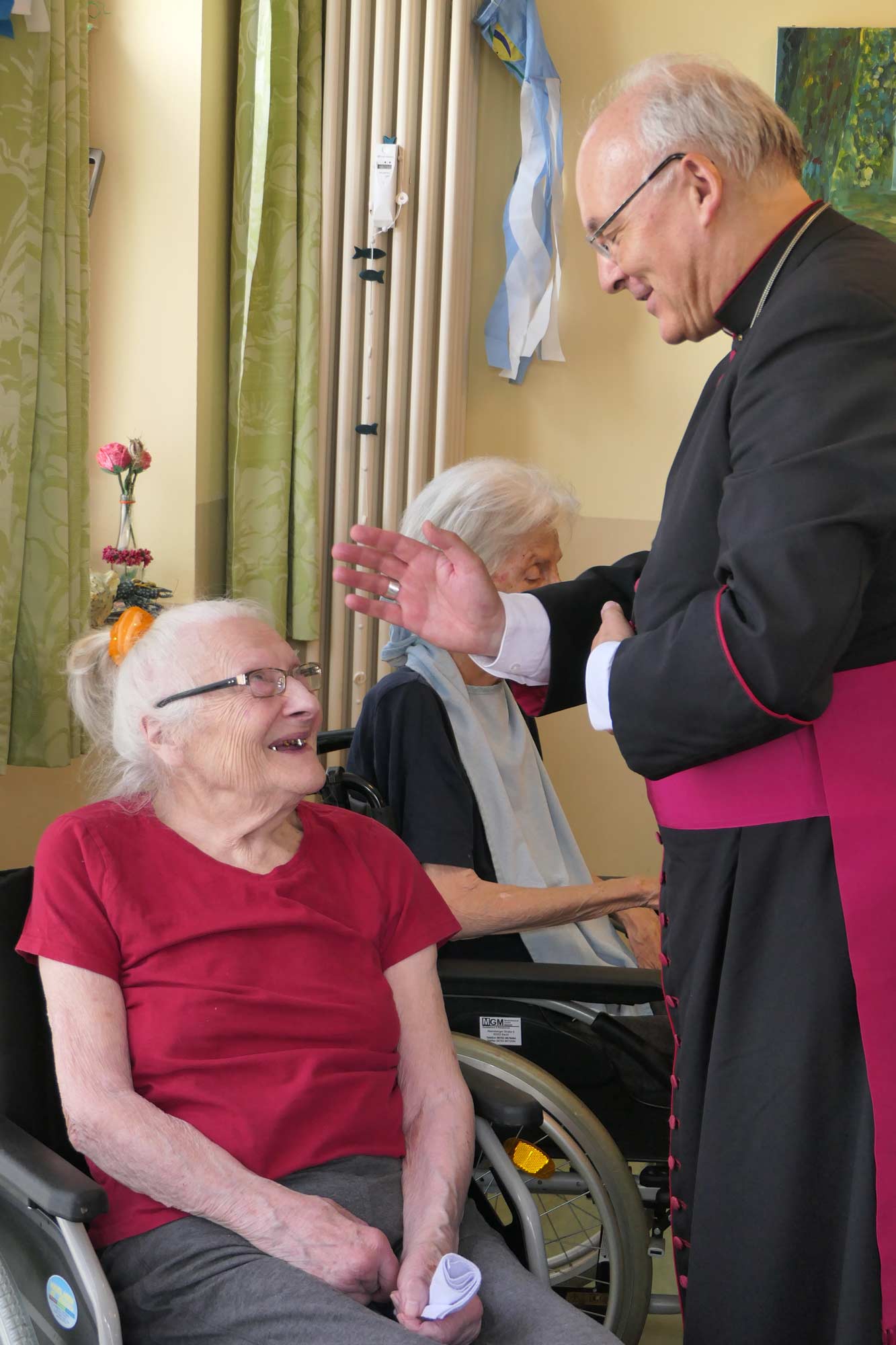 Seniorin im Rollstuhl schenkt Bischof ein Lächeln