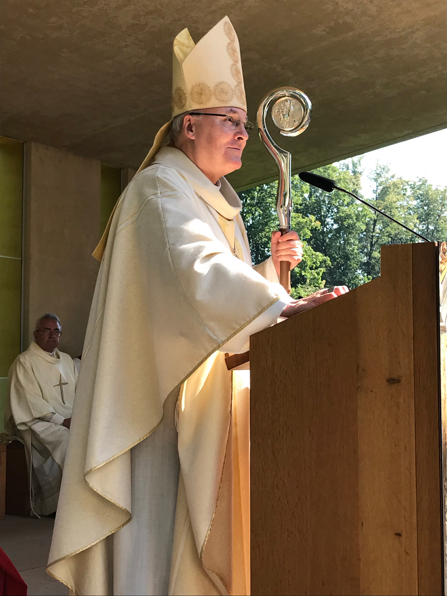 Gute gelaunter, lächelnder Bischof hält eine Predigt beim Freiluftgottesdienst