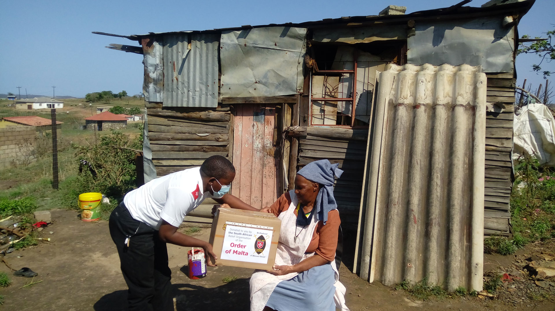 Mitarbeiter der Brotherhood of Blessed Gérard bringt einer südafrikanischen Frau eine Spendenkiste 