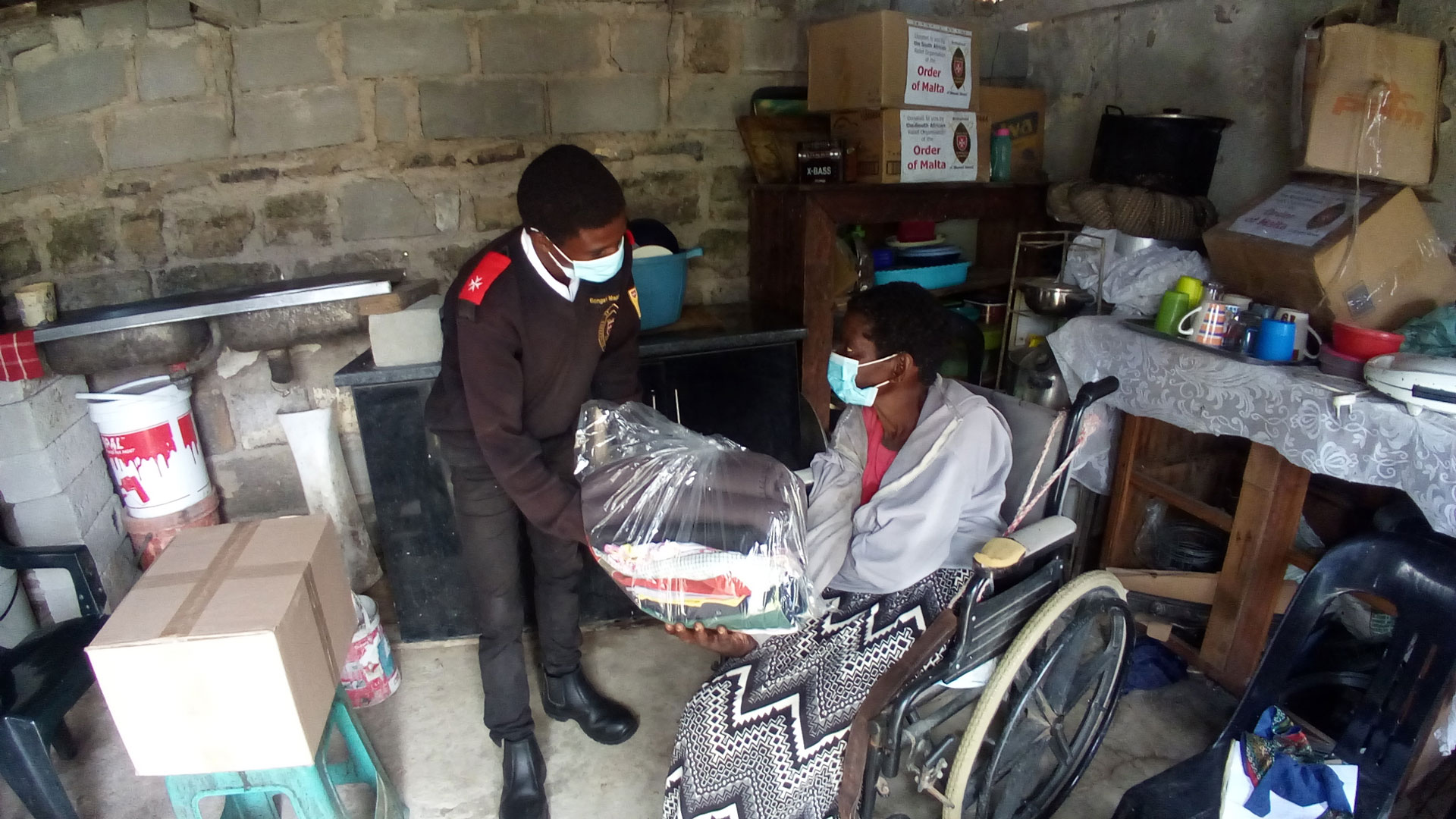 Mitarbeiter der Brotherhood of Blessed Gérard  bringt süsafrikanischer Frau im Rollstuhl Spenden