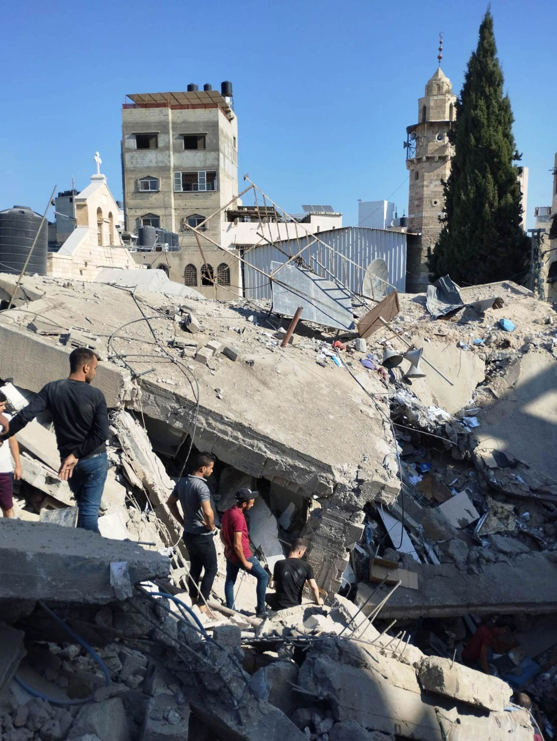 Menschen klettern auf einem zerstörten Gebäude bei der St.-Porphyrius-Kirche in Gaza-Stadt