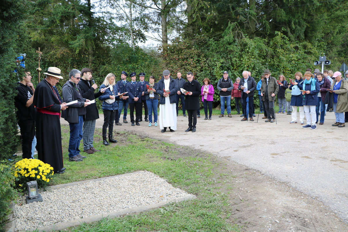 Pilger halten an einer Station und beten im Kreis