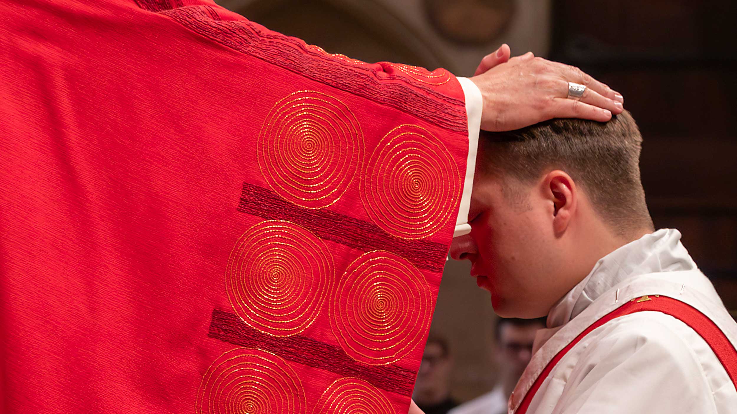 bischof legt priesteramtskandidat die hand auf.