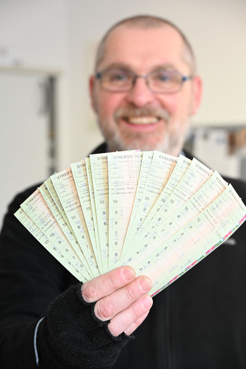 Caritasberater an seinem Schreibtisch zeigt einen Fächer Bustickets
