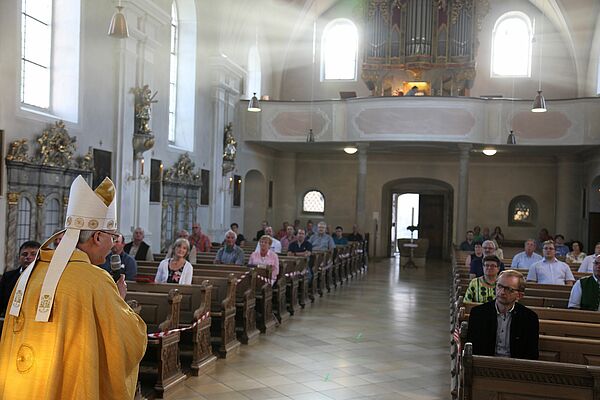 Bischof vor vereinzelten im regulären Abstand sitzenden Gläubigen in den Kirchenbänken