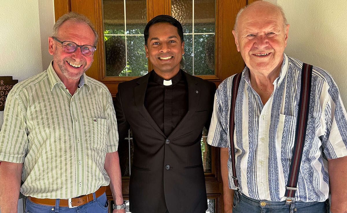 Drei lachende Männer, einer davon Pfarrer