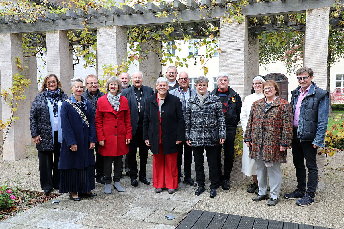 Gruppenfoto pastoraler Mitarbeiter mit Bischof vor Weinstöcken in einem Innenhof