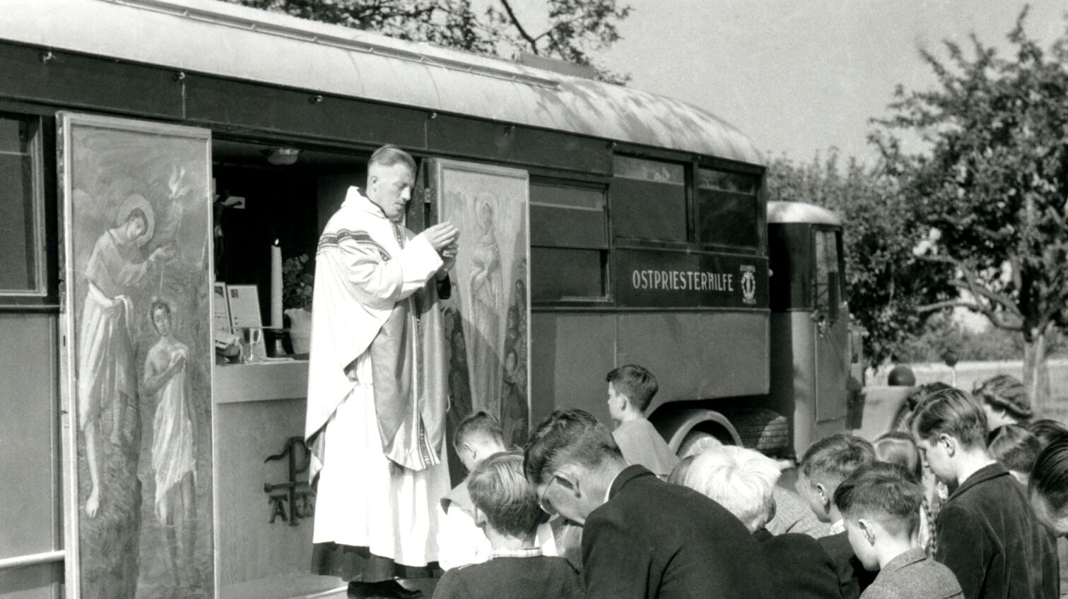 Ein Priester feiert die heilige Messe in den 1950er-Jahren vor einem Kapellenwagen.