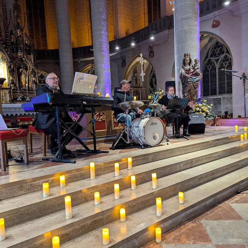 Musiker in einer Kirche, Stufen des Altars voller Kerzen