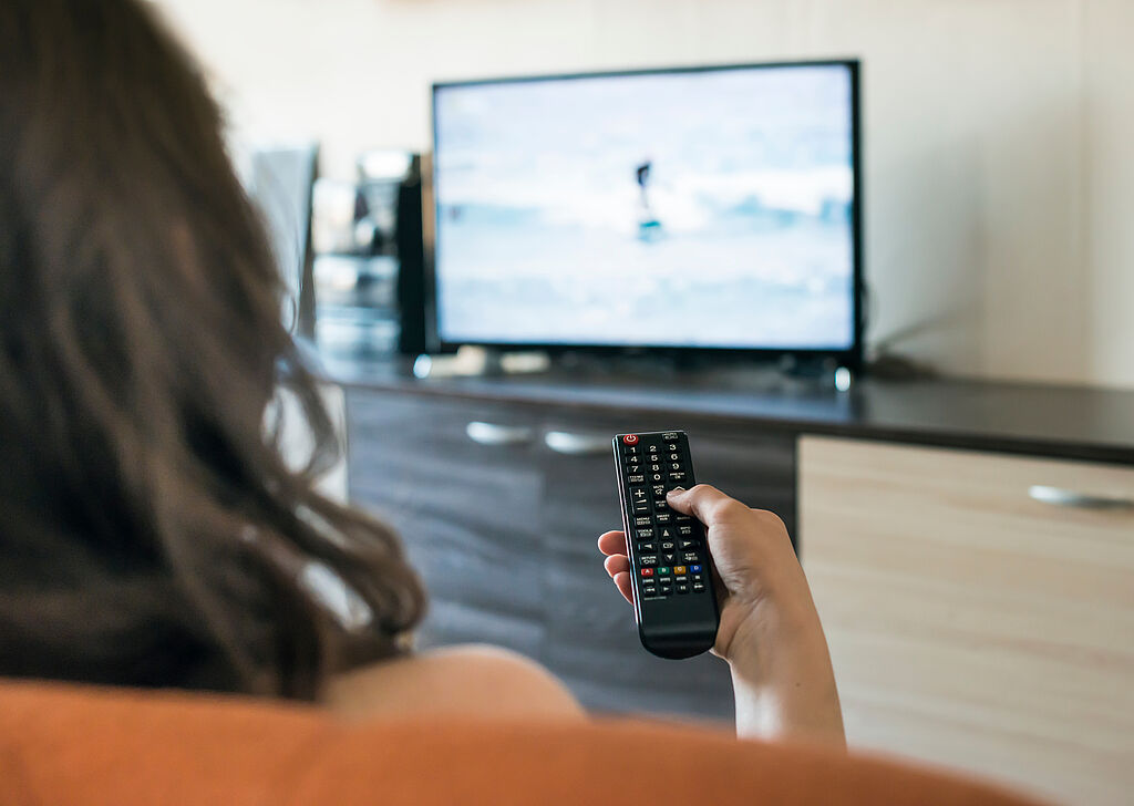 Frau vor dem TV mit Fernbedienung