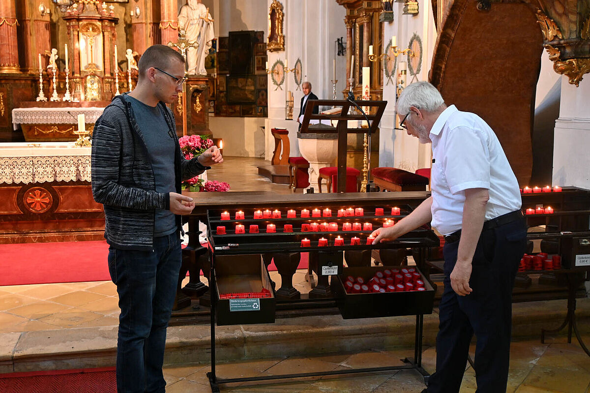 Zwei Männer zünden rote Lichter in der Kirche an