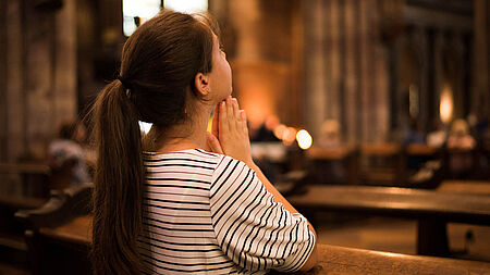 Junge Frau betet in einer Kirche; Hoffnung und Glauben