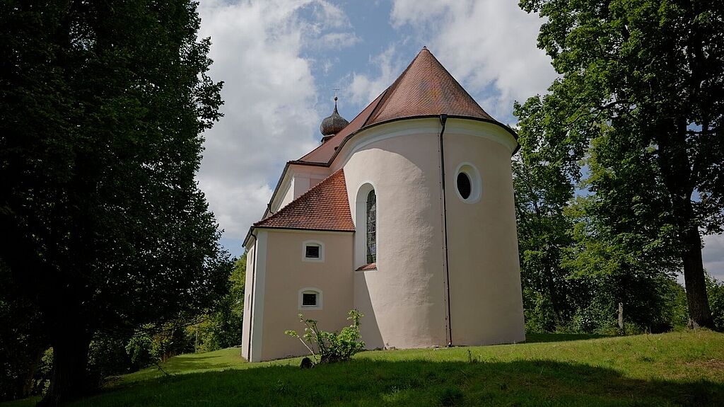 Die Wallfahrtskirche Maria Hilf in Beratzhausen eingerahmt von Bäumen an einem schönen Tag.