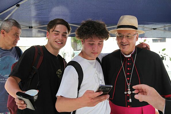 Bischof posiert mit Jugendlichen für Foto