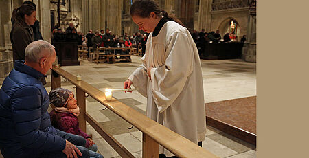 Advent: Ministrantin im Dom zündet die Kerzen der Gläubigen an
