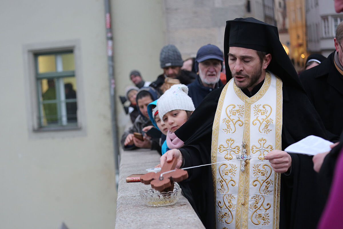 Griechisch-orthodoxer Priester ist im Begriff, ein Holzkreuz von einer Brücke zu werfen