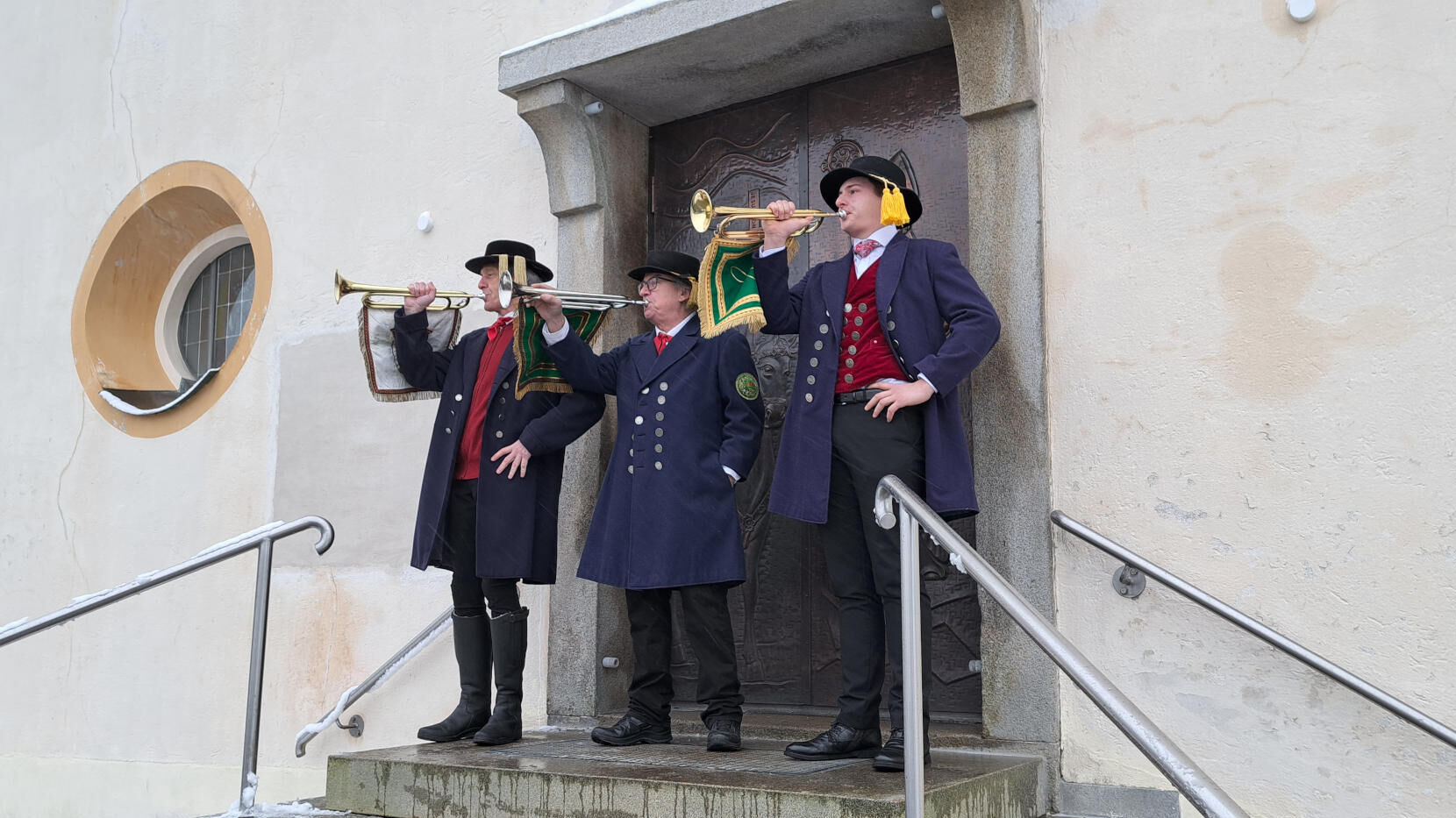 Die Pfingstreiter-Fanfarenbläser spielen vor der Kirche.