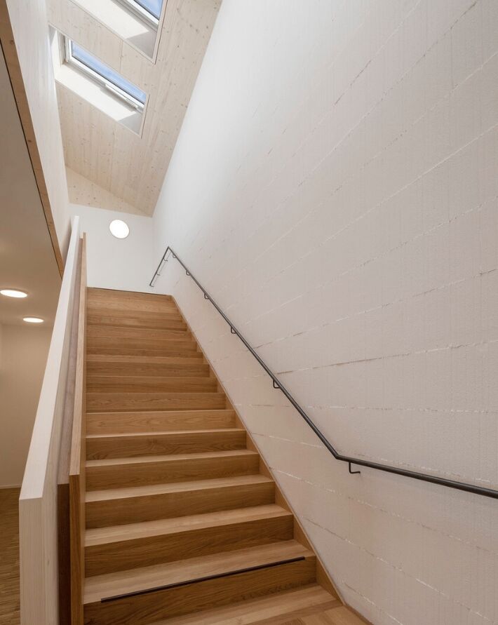 Eine zenital belichtete Treppe stellt die Verbindung zwischen Pfarrsaal im EG und Gruppenräumen her.