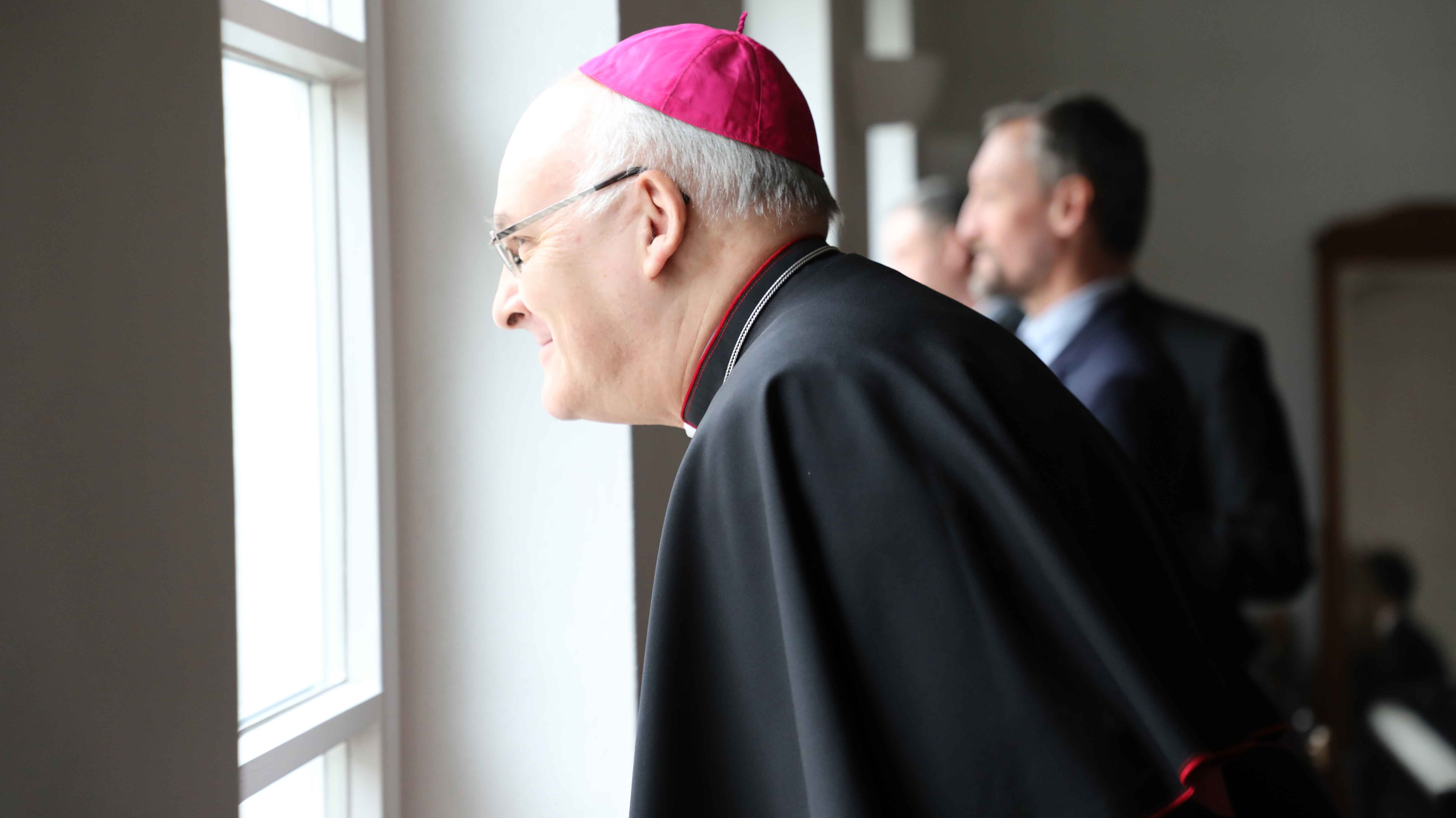 Bischof Rudolf Voderholzer schaut aus einem Fenster der Dr.-Johanna-Decker-Schulen.