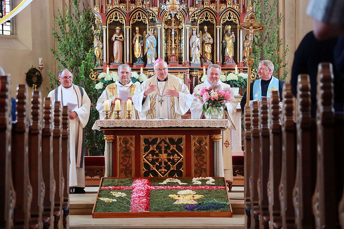 Blick auf den Altar, Priester, davor ein Blumenteppich