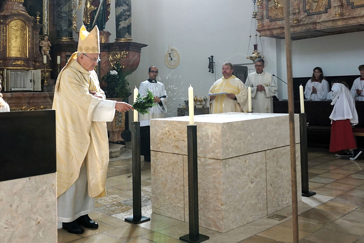 Bischof besprengt Altar mit Weihwasser