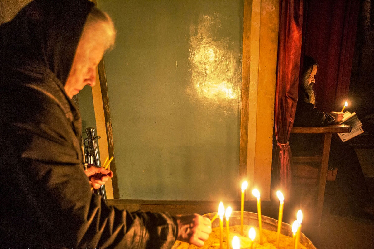 Eine Frau entzündet in der Jerusalemer Grabeskirche eine Kerze
