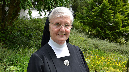 Ältere fröhliche Nonne, Porträt im Grünen